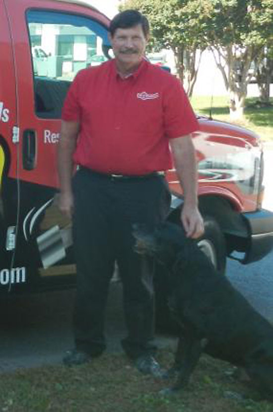 Franchise owner Tim Adams and 'Chief Fun Officer' Rebel the Labrador standing in front of one of Mr. Handyman's distinctive vans