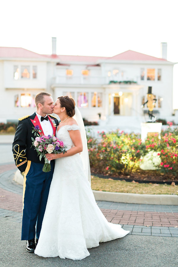 A newly married couple  shares a kiss in front of the beautiful Obici House  and its front flower bed<BR>Photo by Rising Lotus Photography